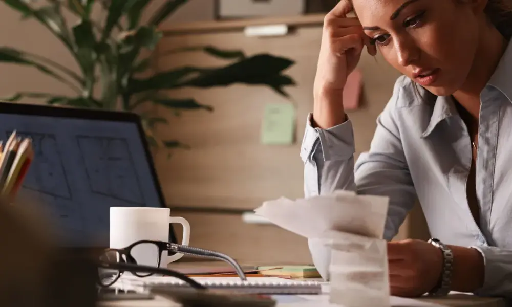 empresaria se sentindo preocupada com dividas financeiras e analisando contas enquanto trabalhava no escritorio